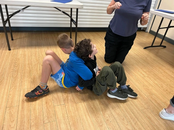 Two boys back to back sitting on the floor